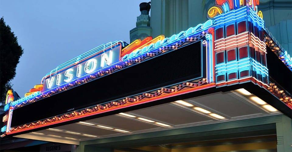 The restored neon marquee of the Vision Theatre glowing at dusk in Leimert Park Village